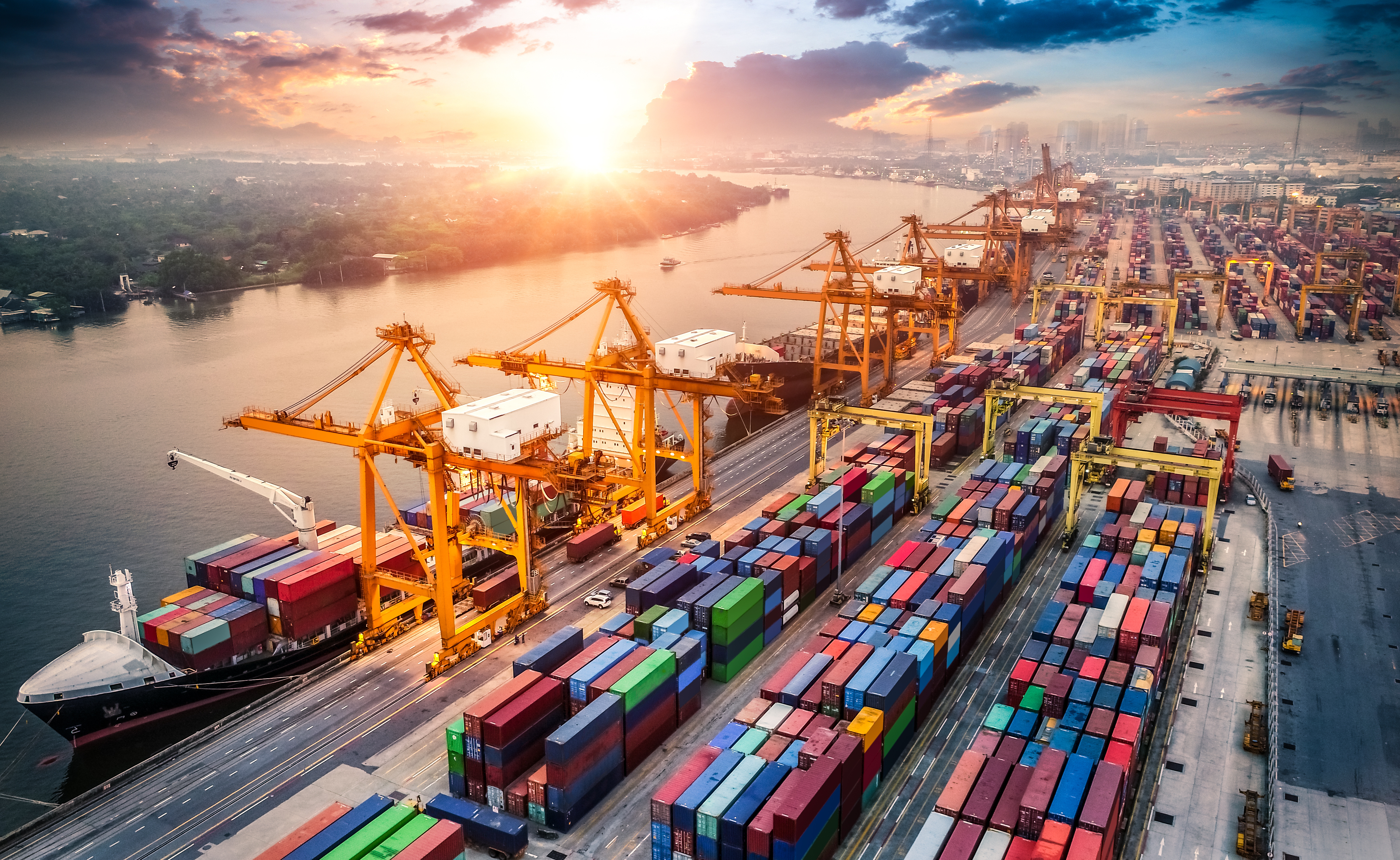 Container terminal at sunset, with cranes loading a cargo ship
